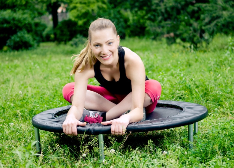 Femme sur une mini trampoline à l'extérieur: Faire du cardio avec une trampoline